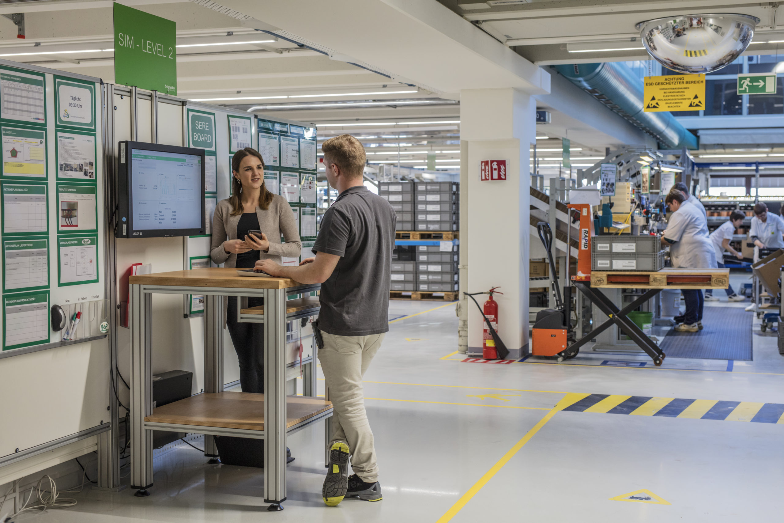 deux personnes en train de parler dans une usine autour d'une table