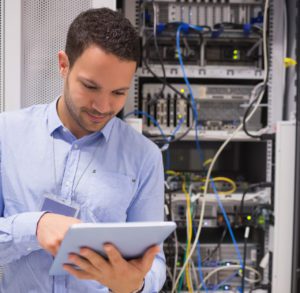 Man in an edge computing data center working on a tablet