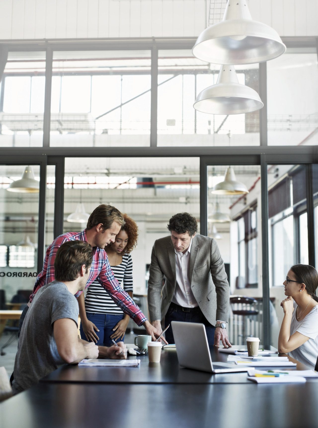 people standing around a laptop in an office