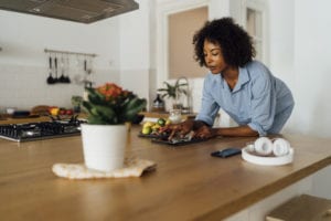 Woman using digital tablet and having a healthy breakfast in her kitchen