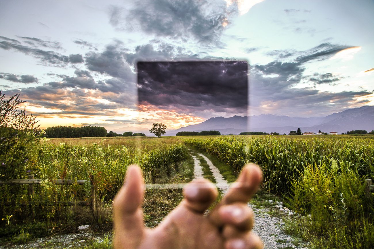 Concept of transparency and climate action. Hand holding a square piece of glass, through which you can see a crystal clear landscape.