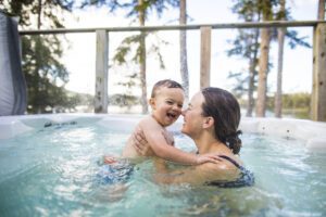 Young boy splashing and playing with mother in swimming pool