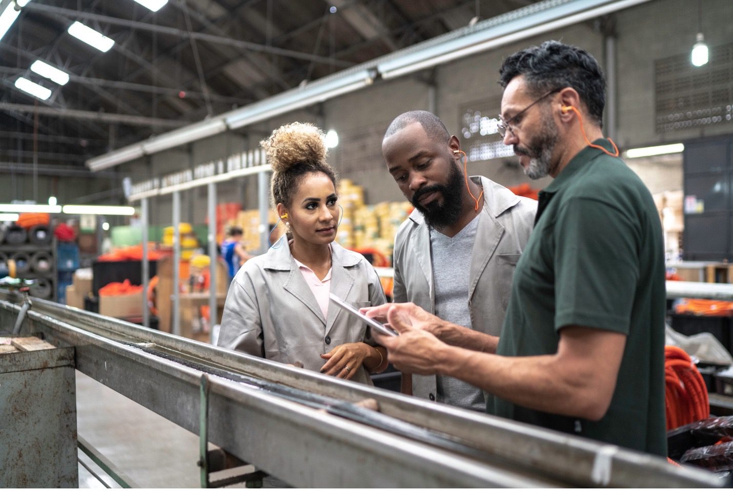 A male manager shares data information on a digital tablet to a male and female employee in a manufacturing facility. digital transformation