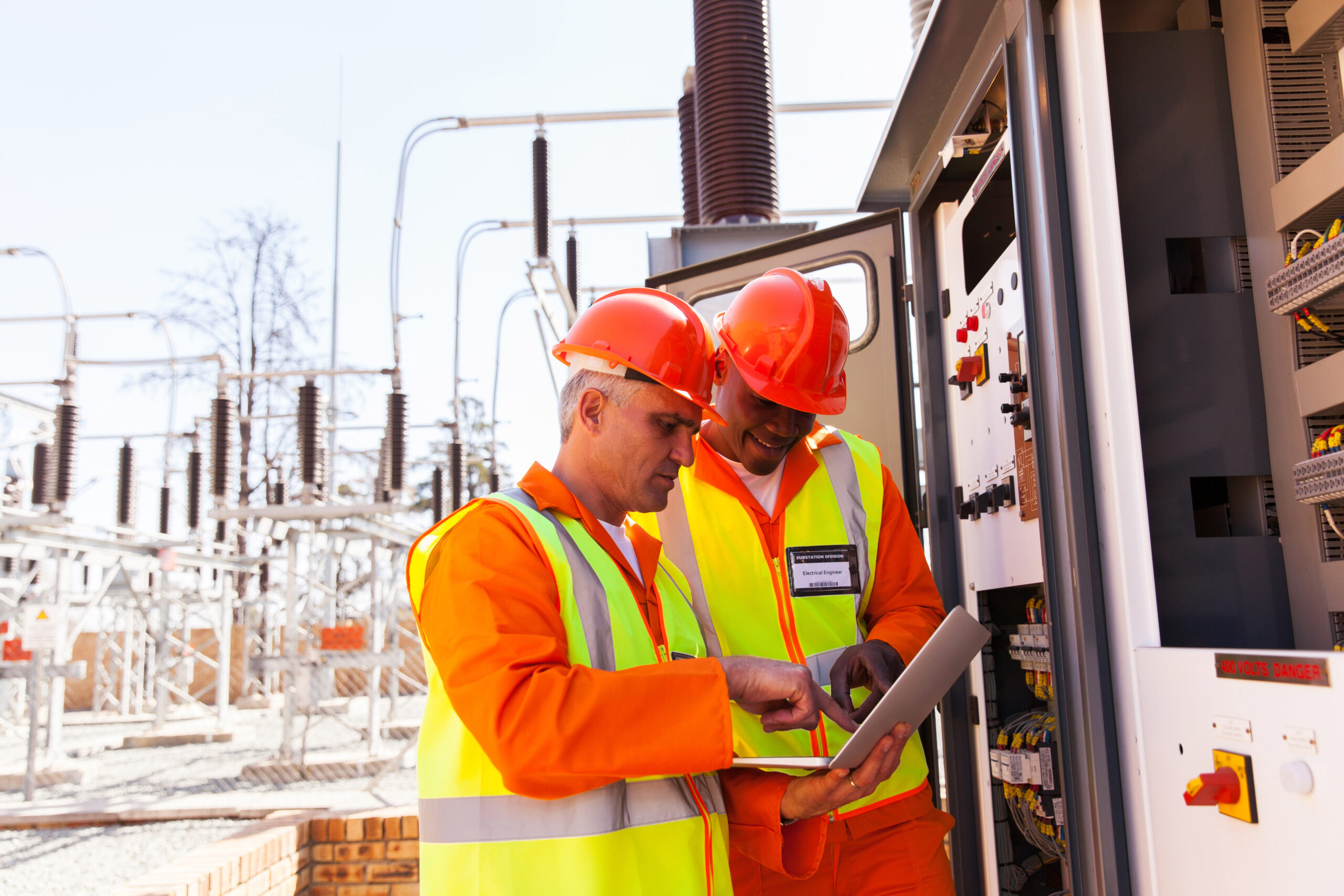 Two electrical engineers wearing hard hats use a laptop computer next to a transformer. An effective transformation of utilities requires the right partners and technology vendors.