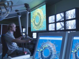 A nuclear reactor scientist holds controllers while watching computer screens displaying the reactor. Transformer monitoring and reliability are essential for large or critical energy user facilities to ensure continuity and reduce operational risks.