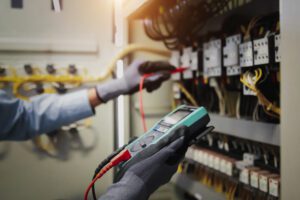 Engineer hand holding AC multimeter checking electric current voltage and looking for power quality issues at circuit breaker terminal