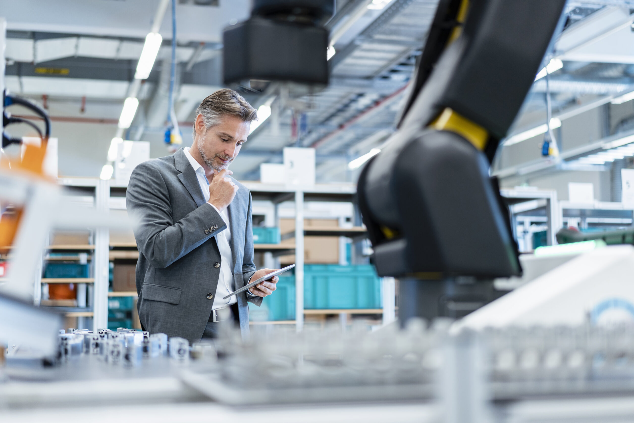 Businessman with tablet in a modern factory hall displaying open automation