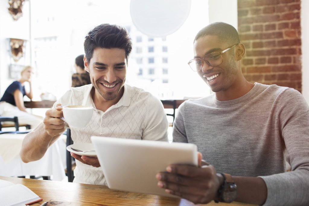 Two men looking at tablet showing their managed distributed IT edge computing sites.