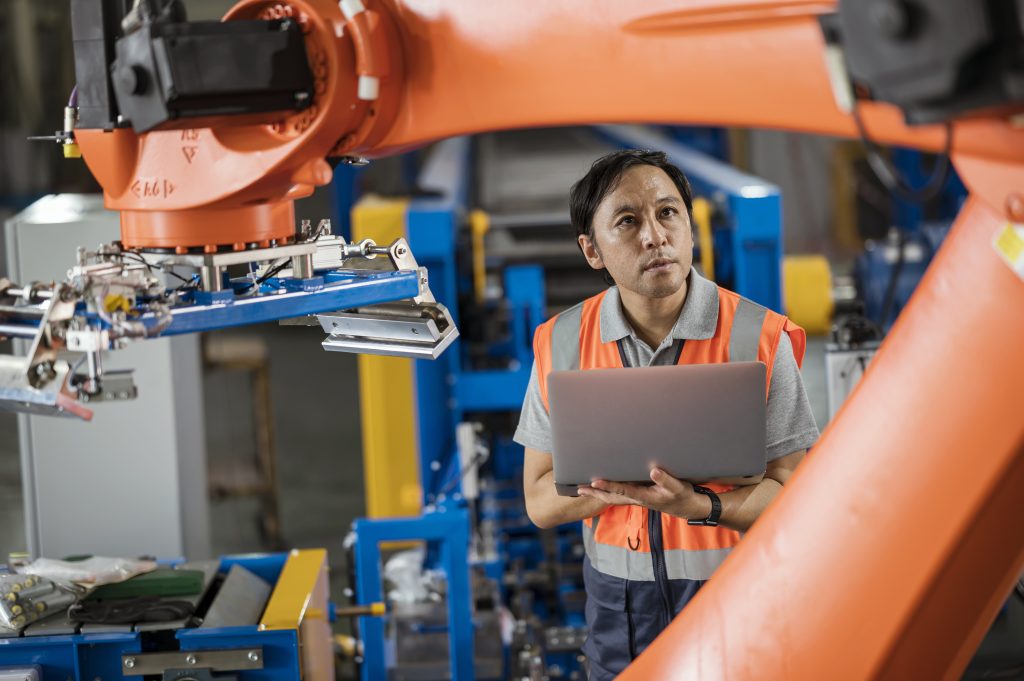 An engineer uses a laptop computer inside a factory. 