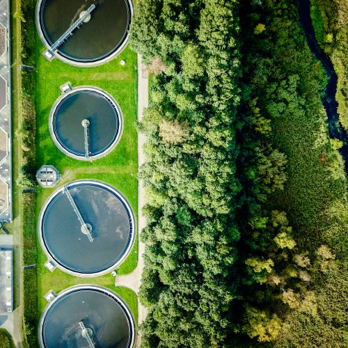 Aerial shot of sewage treatment plant placed near a river, Denmark. Aerial view shot with drone.