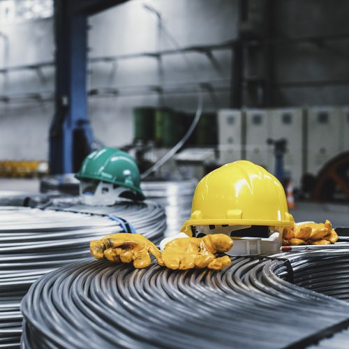 hard hats sit on Heavy Machinery and steel cable processing equipments at the empty manufacturing plant in the factory warehouse.