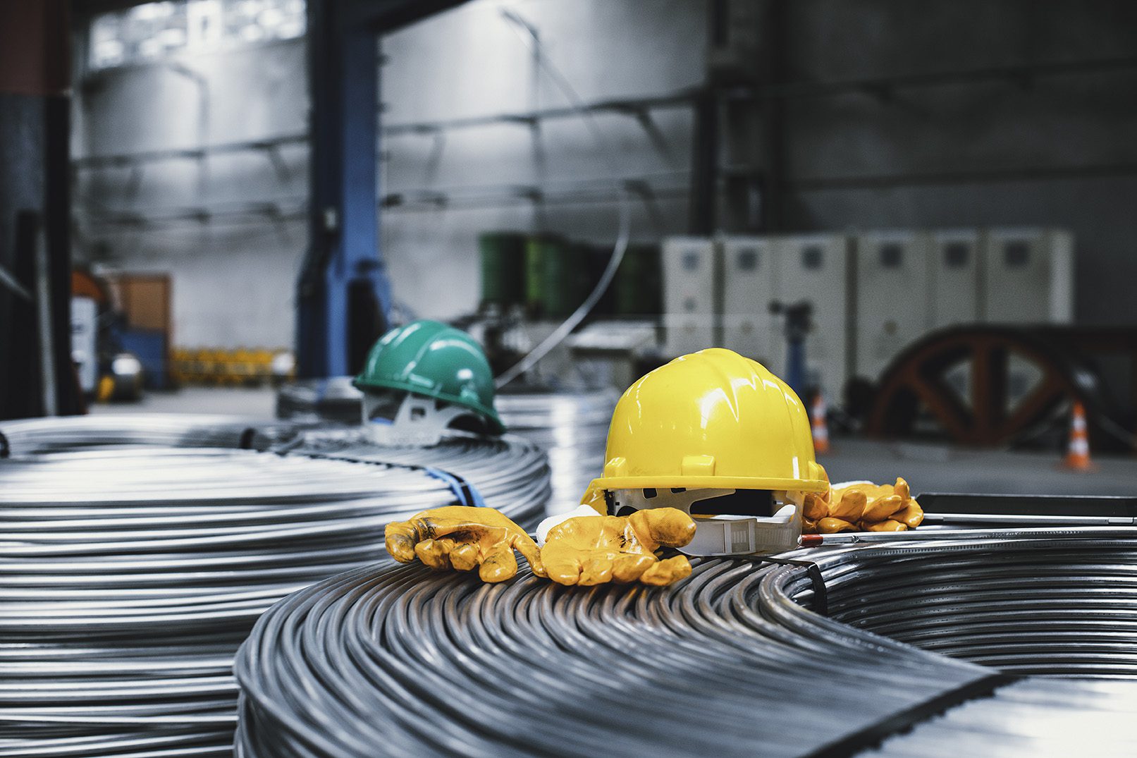 hard hats sit on Heavy Machinery and steel cable processing equipments at the empty manufacturing plant in the factory warehouse.