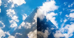 Modern glass office building with cloud landscape to abstractly represent the cloud computing landscape.