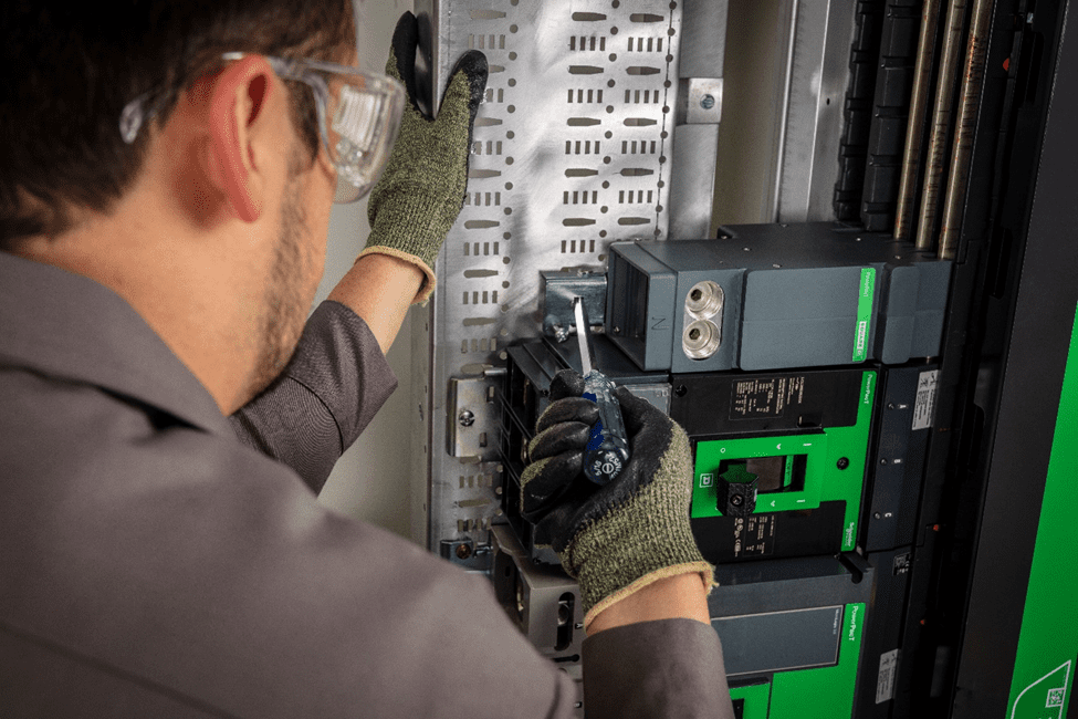 A serviceman working on a low-voltage switchboards with a screwdriver.