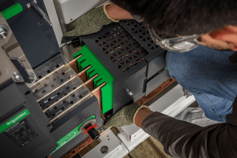 A serviceman working on low-voltage switchboards with a screwdriver.