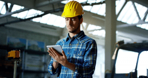 An engineer using a digital pad with an industrial background.