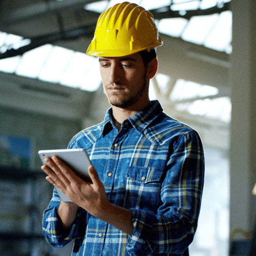 An engineer using a digital pad with an industrial background.