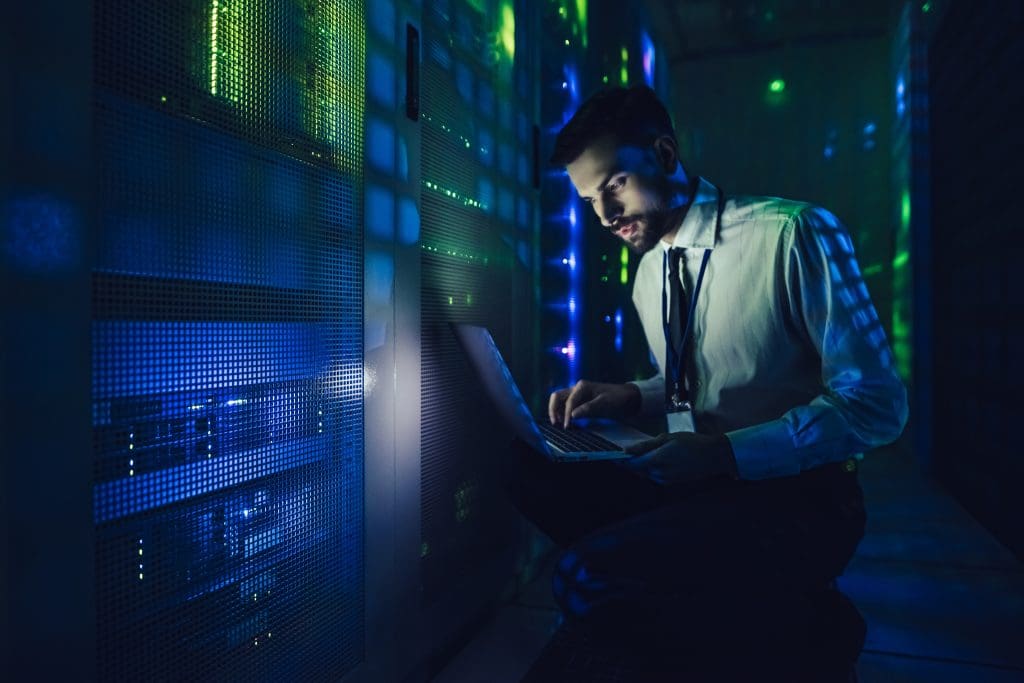 Technician examining server with CoreSite in big data center full of rack servers.