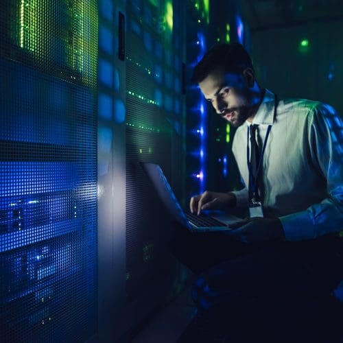 Technician examining server with CoreSite in big data center full of rack servers.