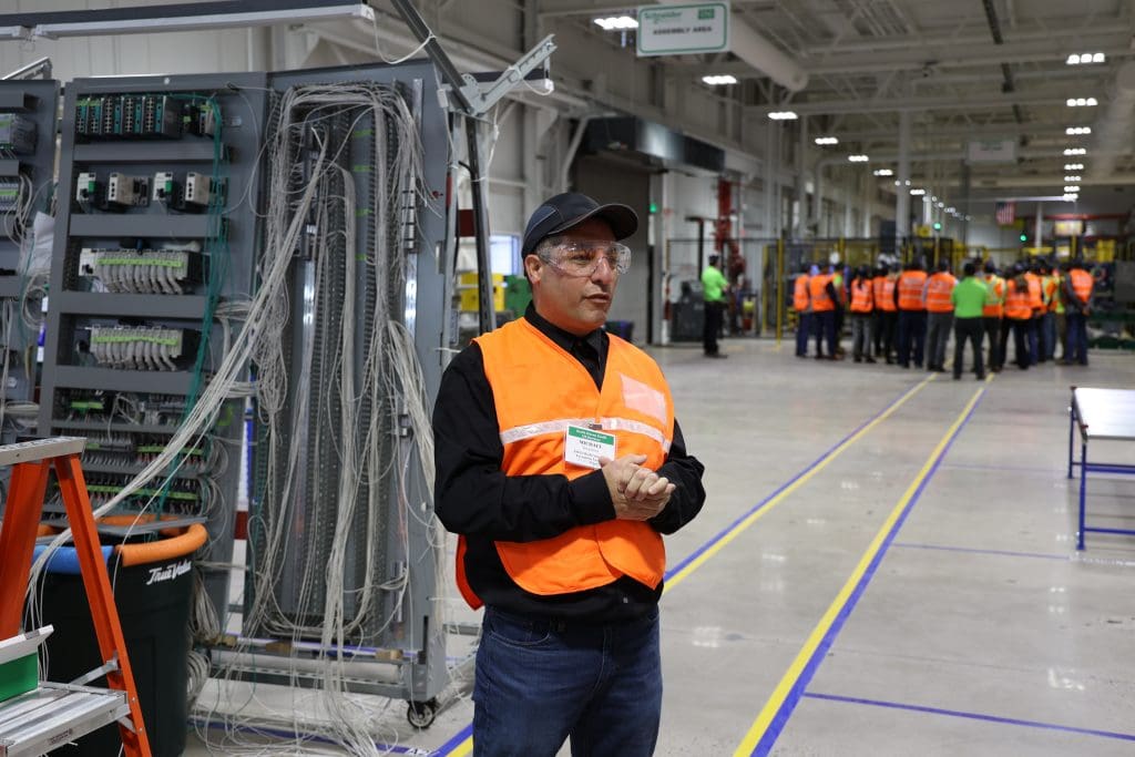 A man in an orange safety vest stands next to switchgear in the EcoFit facility in North Haven, Connecticut