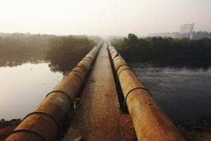 water pipeline across a body of water with trees in the background