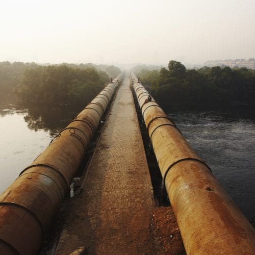 water pipeline across a body of water with trees in the background