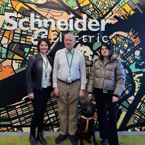 Schneider Electric employees Paulette Ricciardone, Rick Blair, his Seeing Eye® Dog Xylene, and Marina Vassalo pose for a photograph at the Schneider Electric Boston City Hub