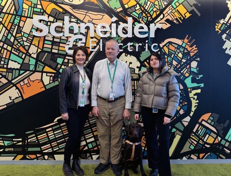 Schneider Electric employees Paulette Ricciardone, Rick Blair, his Seeing Eye® Dog Xylene, and Marina Vassalo pose for a photograph at the Schneider Electric Boston City Hub