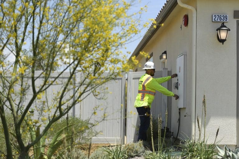 Electrician working on an electrical panel outside a residential home.