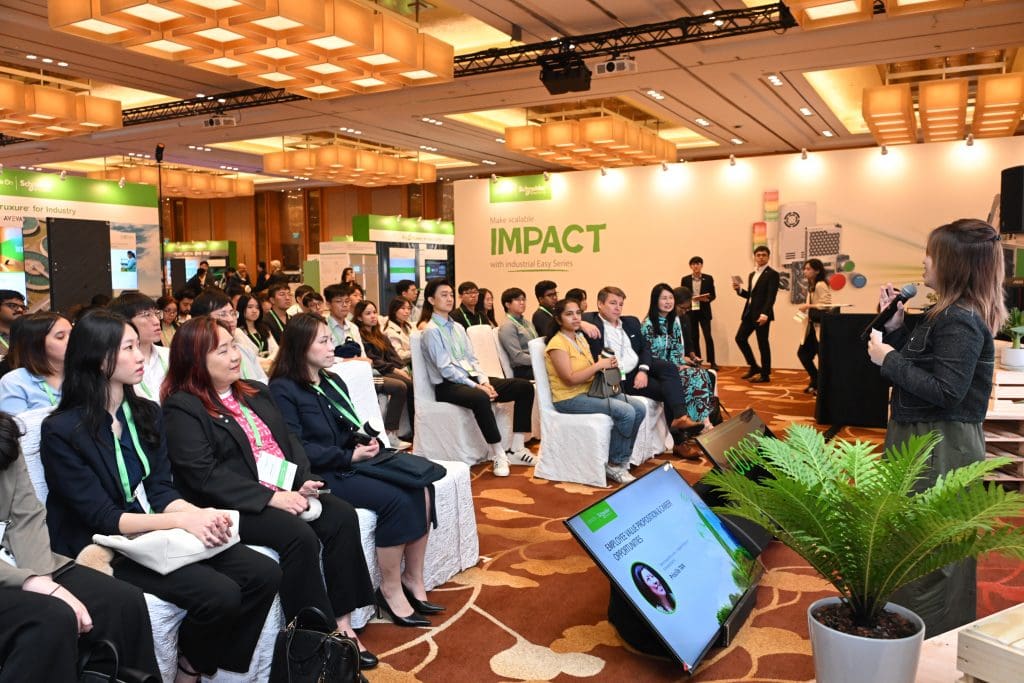 People in an audience sitting and listening to a speaker presenting