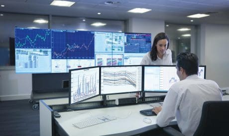 Financial analysts working with graphs on screens in control room