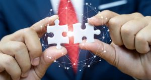 man holding two puzzle pieces coming together to depict IT infrastructure partnership
